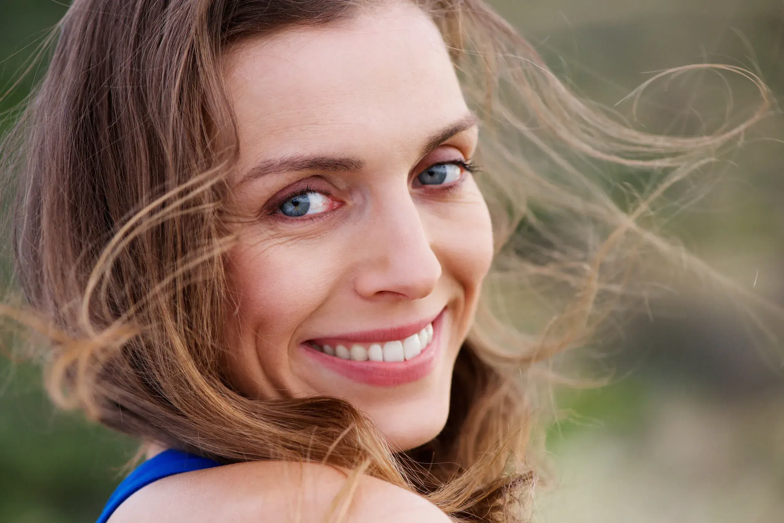 Woman with radiant youthful skin smiling outdoors - wrinkles and anti-aging treatments at ANU Face Mind Body Elizabethtown KY
